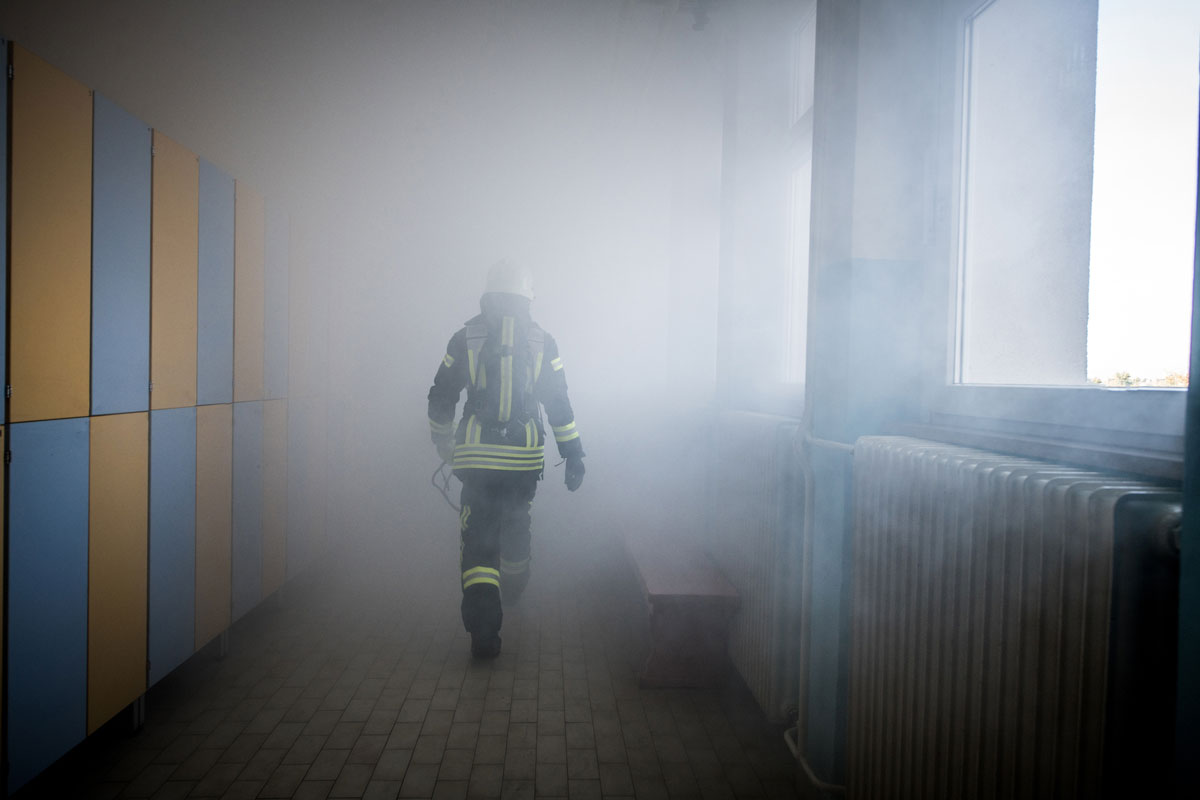 En person med brandutrustning som går genom rök.
